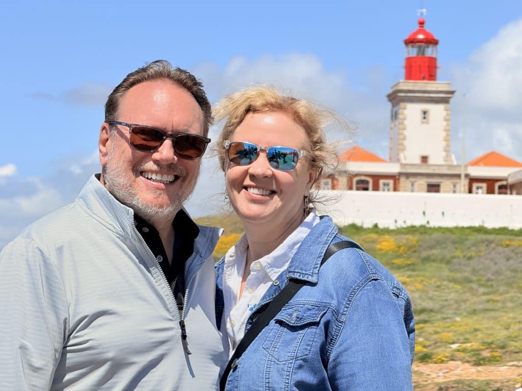 Two visitors taking a selfie with Cabo da Roca lighthouse behind them