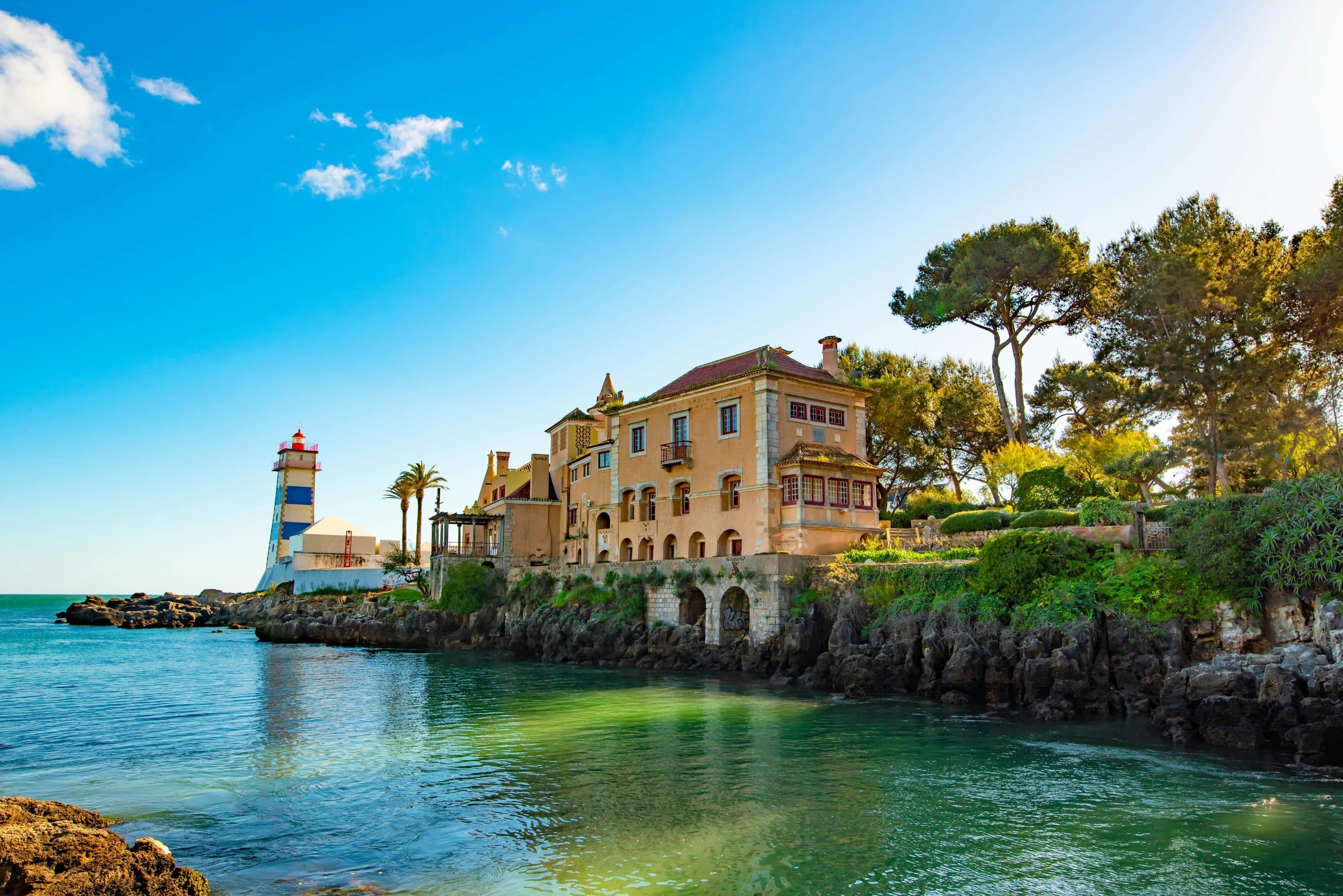 Farol de Santa Marta, prédios costeiros e água turquesa em Cascais