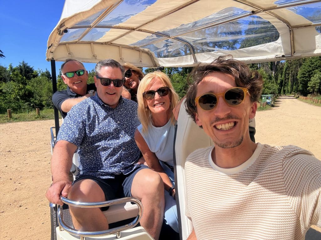 A guide and visitors taking a selfie beside their private tour vehicle