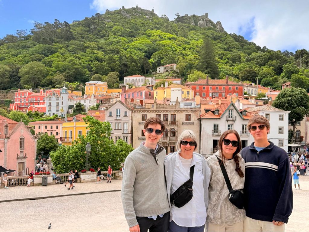 Four visitors in Sintra town with colourful buildings and a wooded hillside behind them