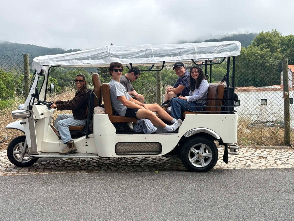 A guide and visitors in a white covered private tour vehicle