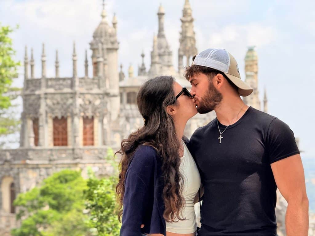 A couple kissing with Quinta da Regaleira palace behind them