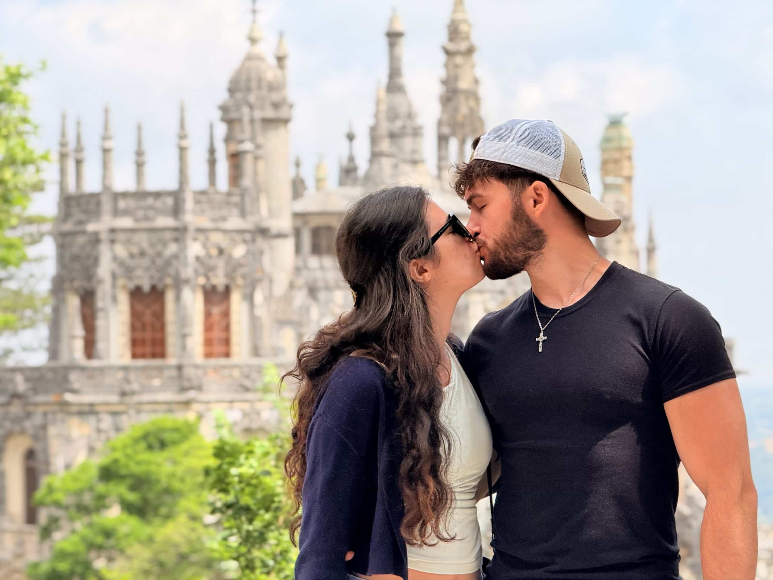 Um casal beijando o palácio Quinta da Regaleira atrás deles.