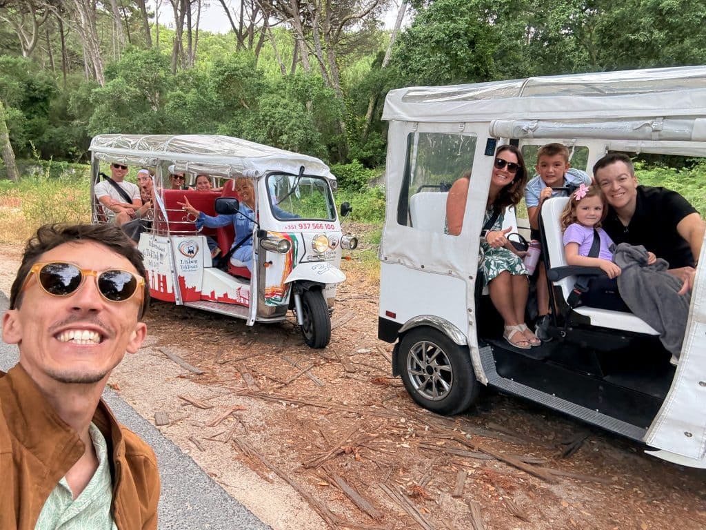 Visitors posing beside two private tour vehicles in a wooded area