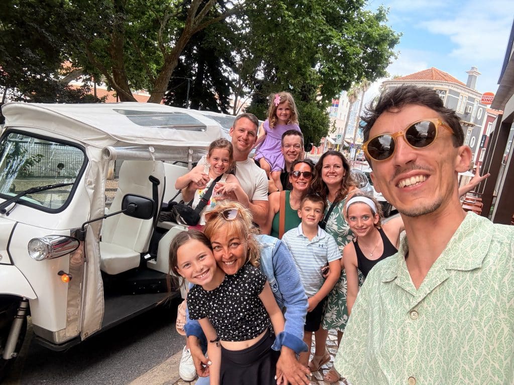 A family and guide beside a white covered tour vehicle in Sintra
