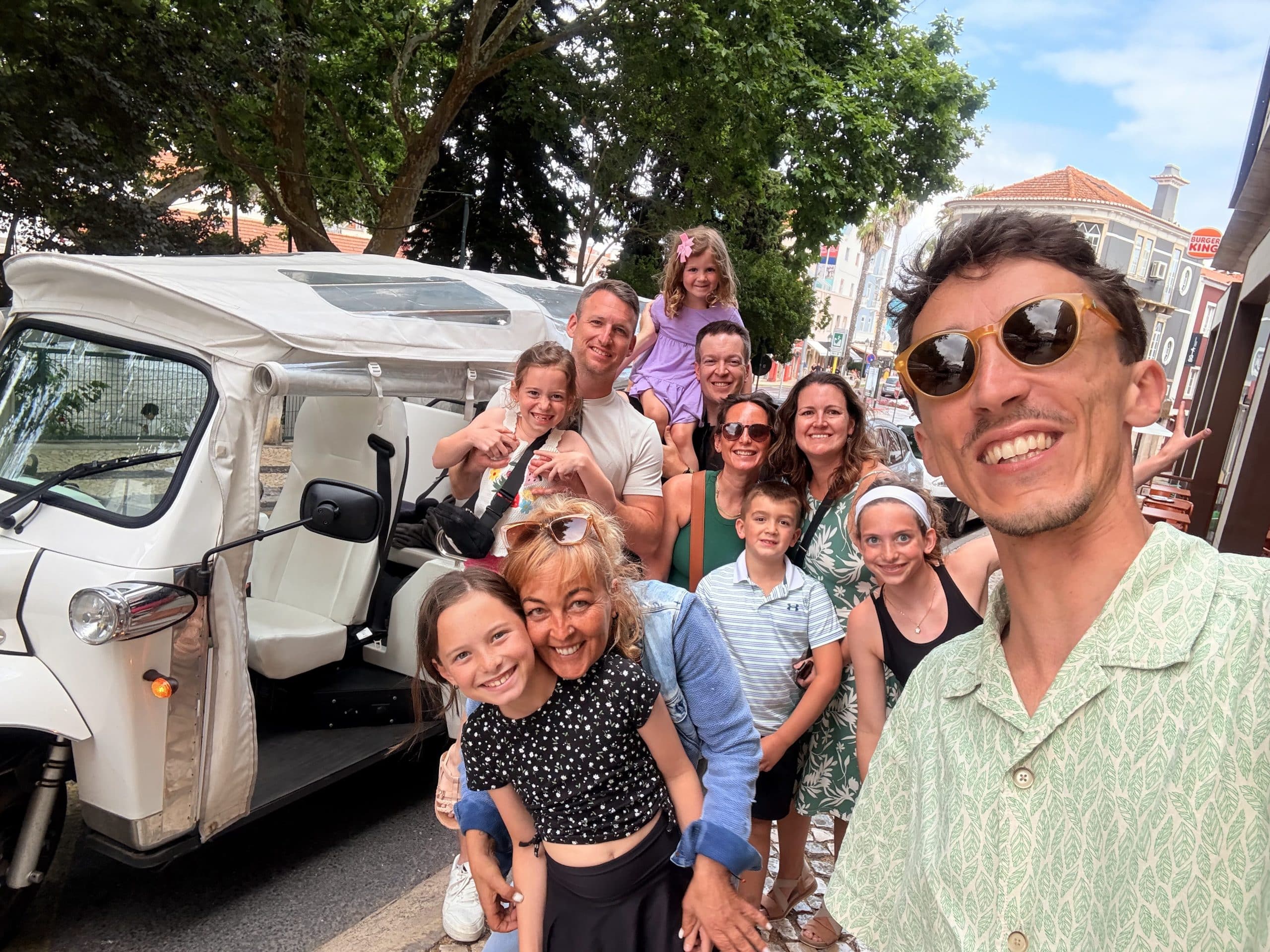 Uma família e guia ao lado de um veículo branco coberto em Sintra