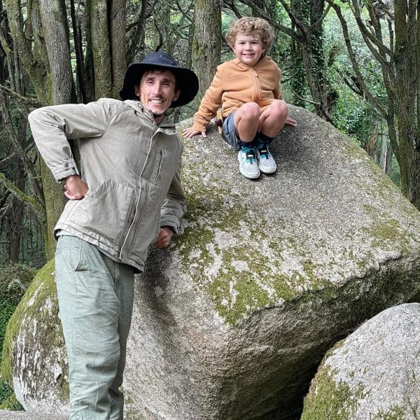 Daniel Ponce with a young boy on a large mossy boulder in the Sintra forest, Portugal โ enjoying a nature break during a private family-friendly tour with Yes, You Deserve!