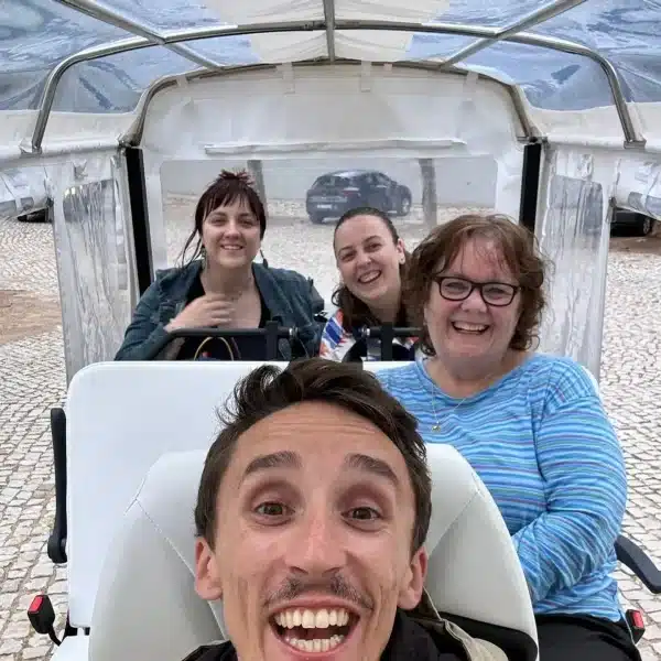 Smiling tourists enjoying a private Sintra tuk tuk tour with their guide from Yes, You Deserve! on a cobblestone square in Portugal.