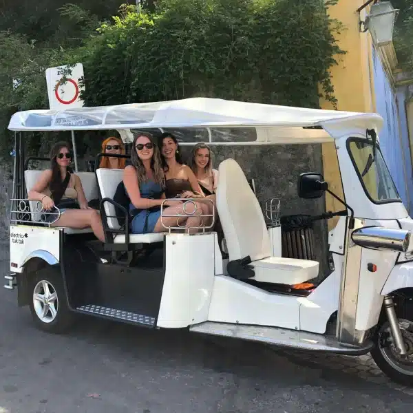 Group of friends smiling on an electric tuk tuk tour in Sintra, Portugal, ready to explore the townโs magical streets with Yes, You Deserve.