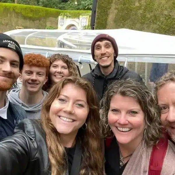 Group of smiling tourists enjoying a tuk-tuk tour in Lisbon with their local guide โ Yes, You Deserve! private tours for families and groups.